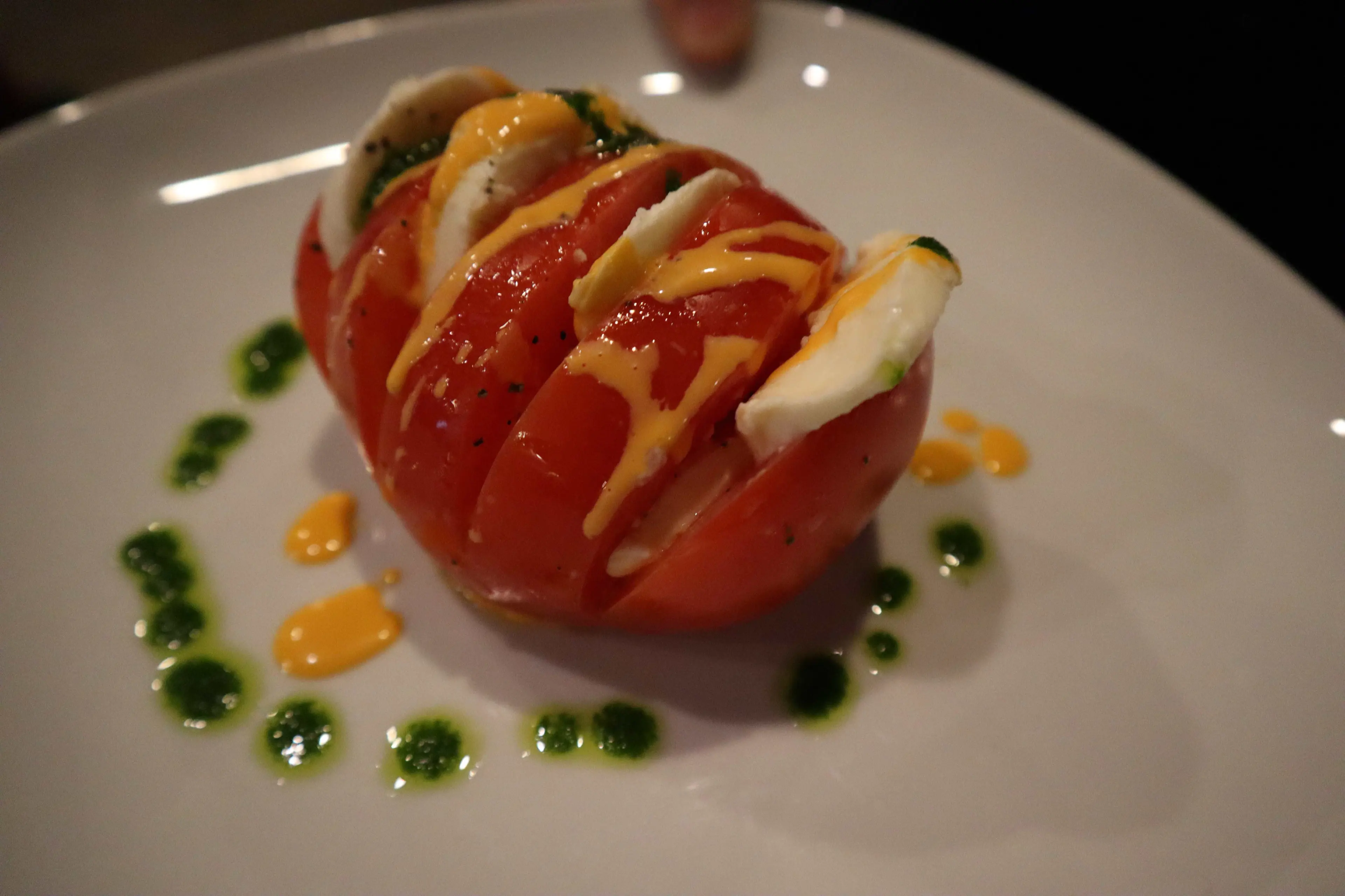 Hasselback caprese with tomato, mozzarella, and basil oil